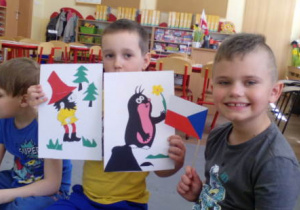 Dwaj chłopcy trzymają flagę Czech i obrazki bajek czeskich.